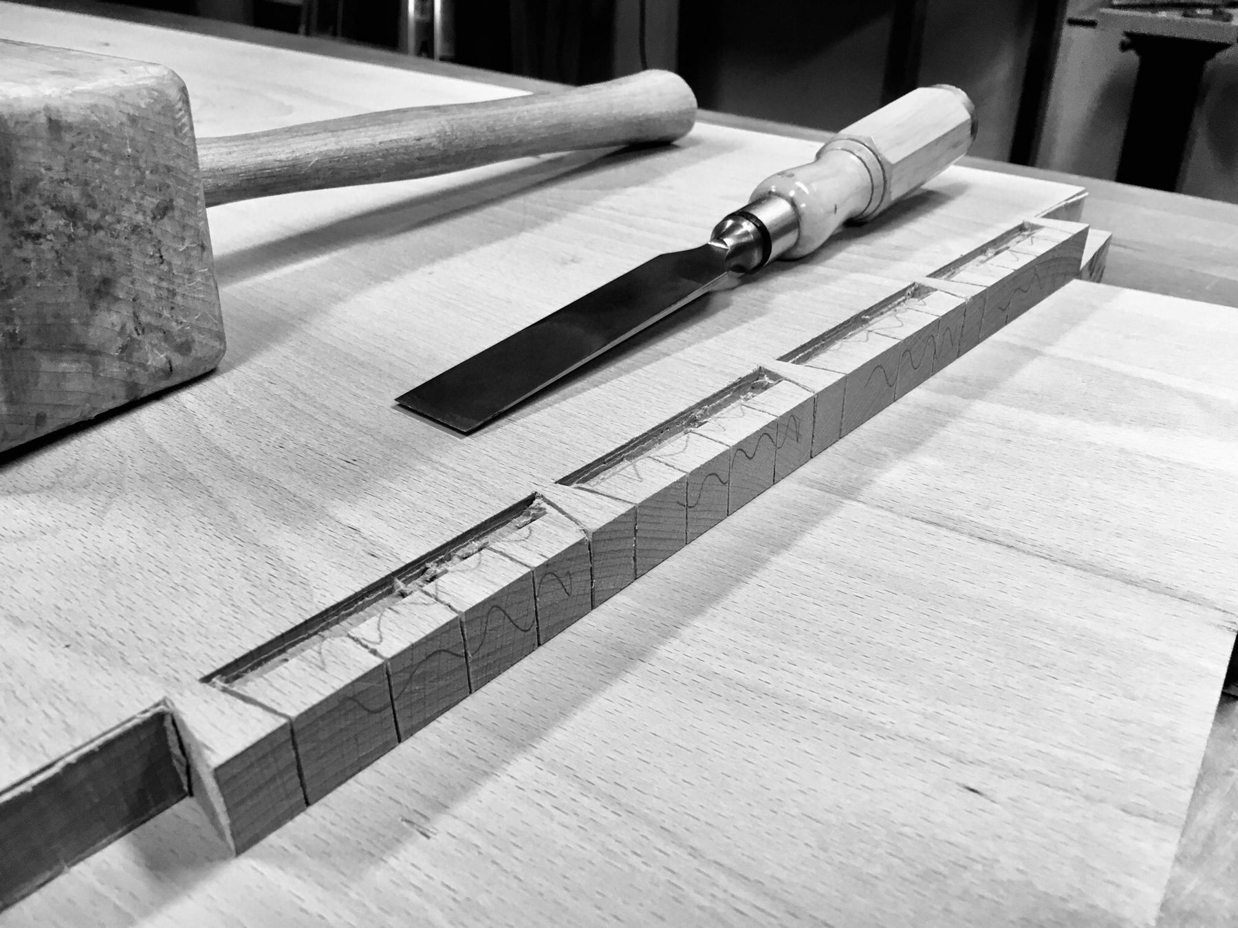 Mallet and chisel beside a row of hand-cut dovetail joints