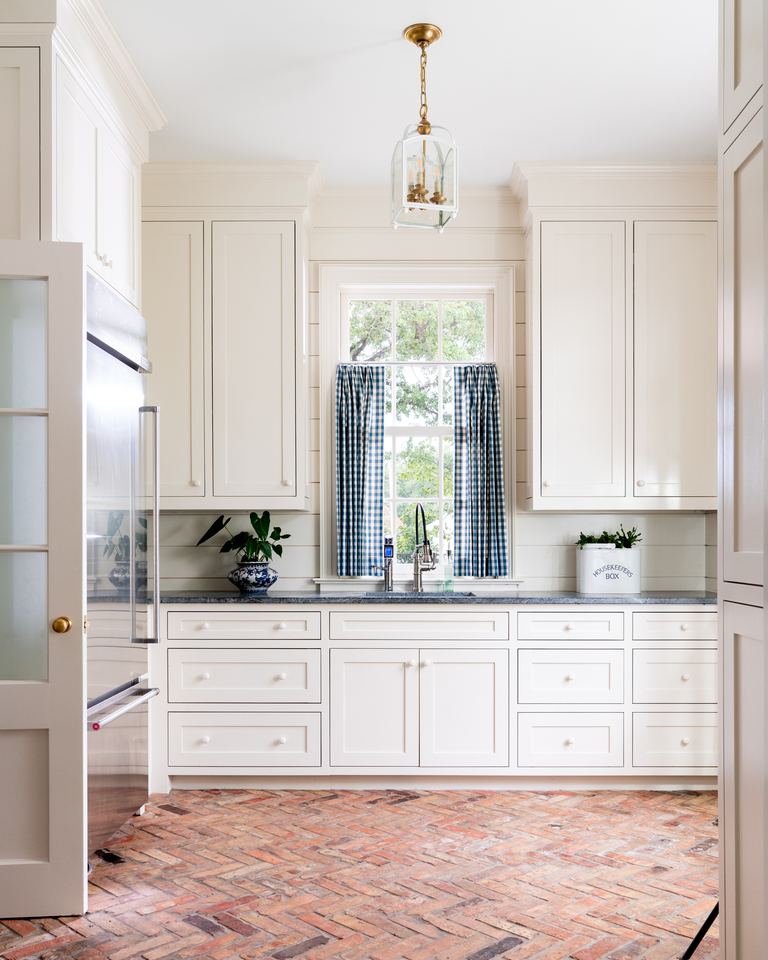 Scullery with painted cabinets and a brick floor