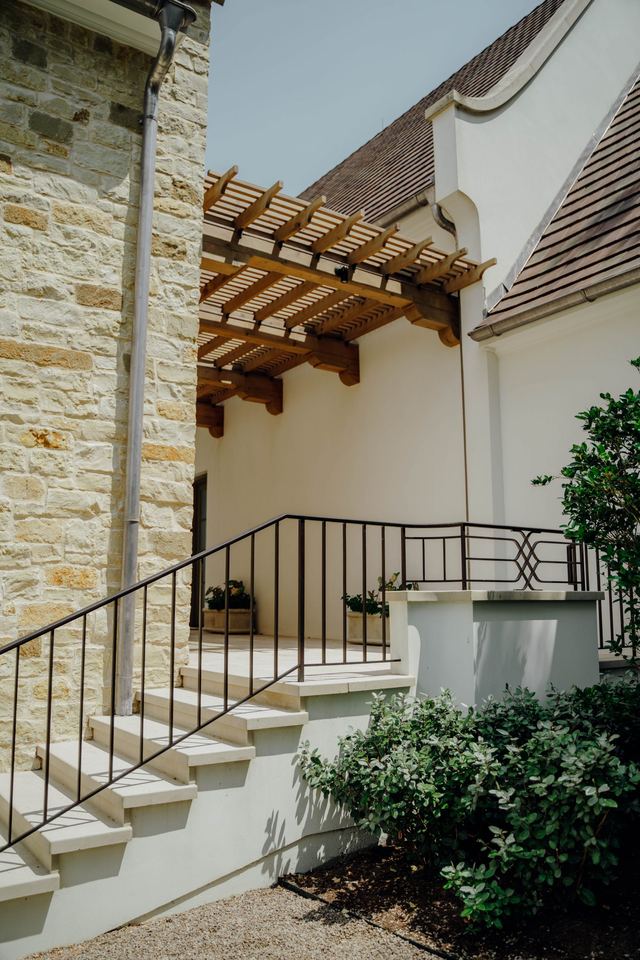 Stone stair with iron rail beside a timber pergola