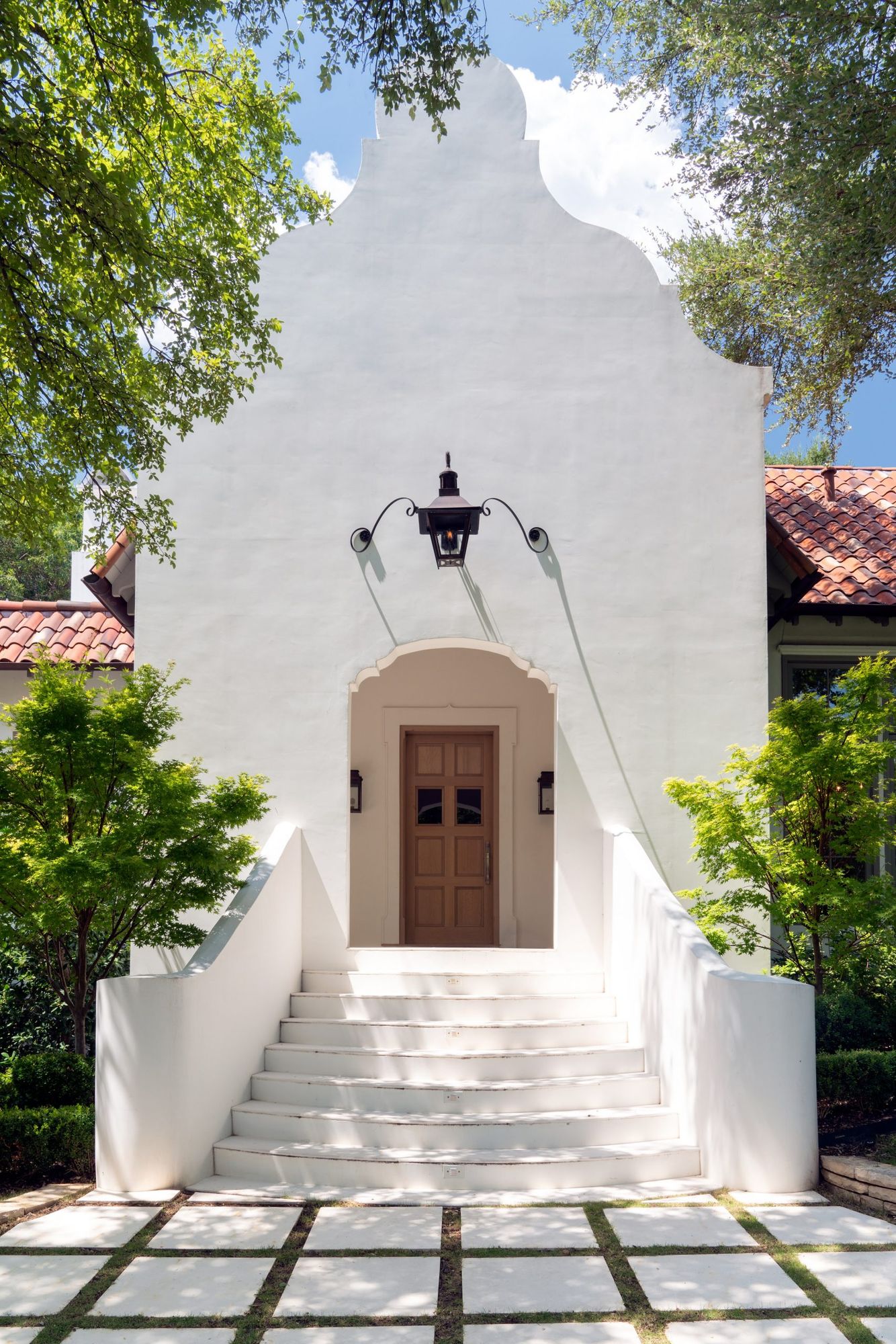 Scalloped white gable over a stair and arched front door