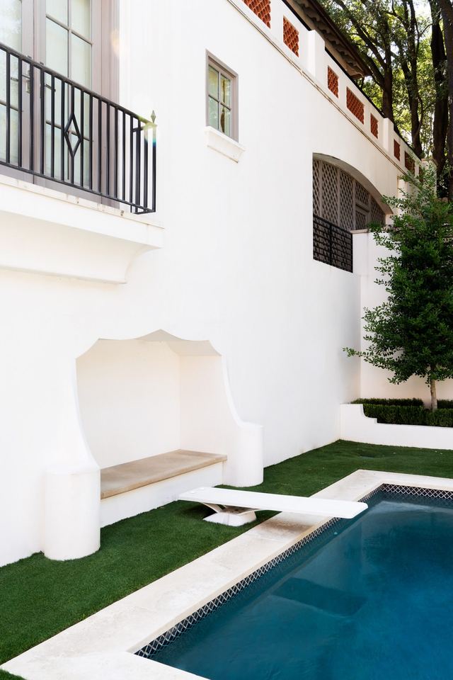 Pool along a stucco wall with a balcony above