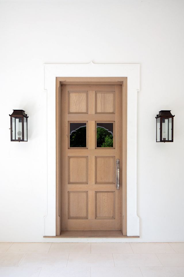 Wood front door between two lanterns