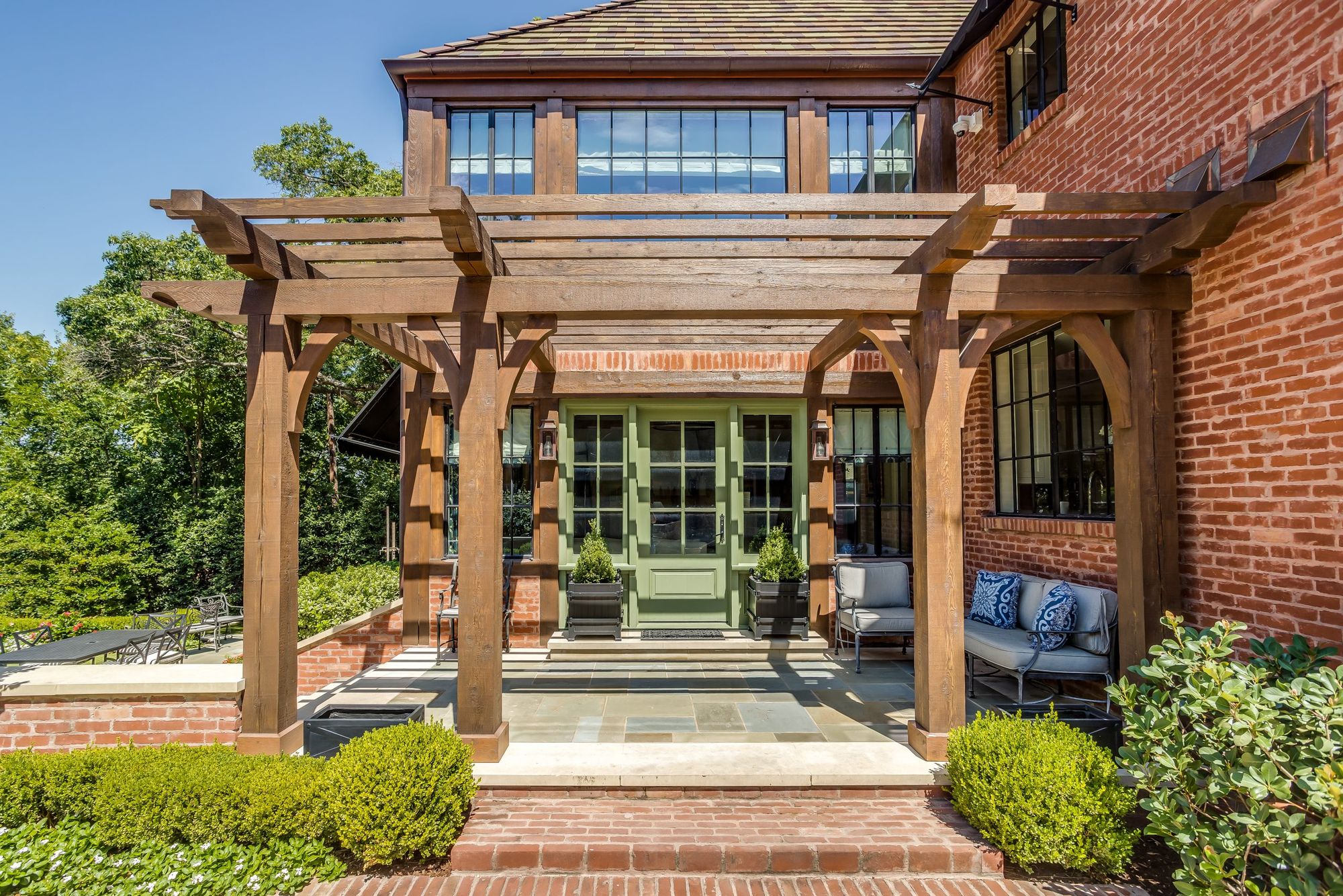 Cedar pergola over the garden entry of a brick house