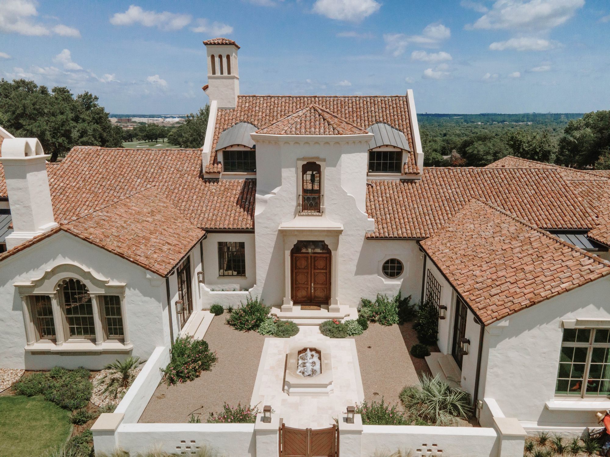 Aerial view of a white stucco courtyard house with clay tile roofs