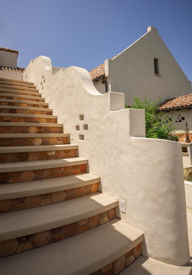 Open stair climbing a stepped stucco wall
